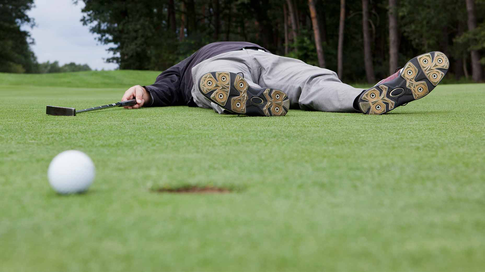 frustrated golfer laying down on putting green