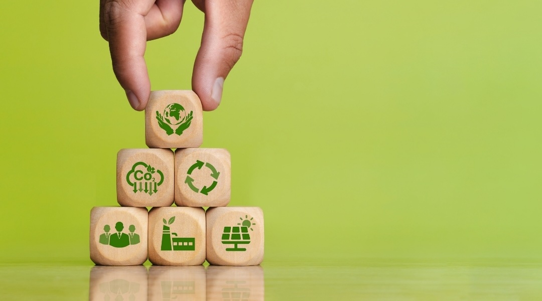 cubes de bois en pyramide sur un fond vert qui imagent l'économie circulaire et la réduction de l'empreinte carbone