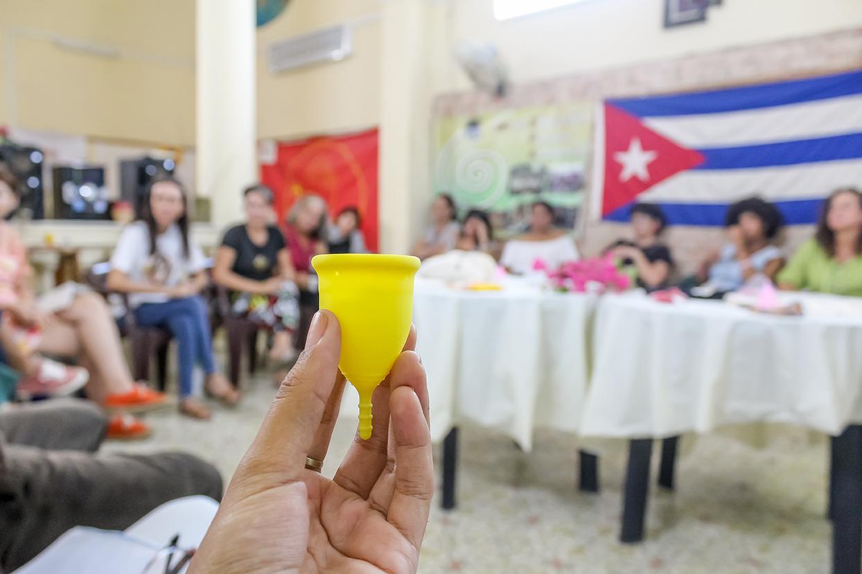 A person holding a yellow menstrual cup

Description automatically generated