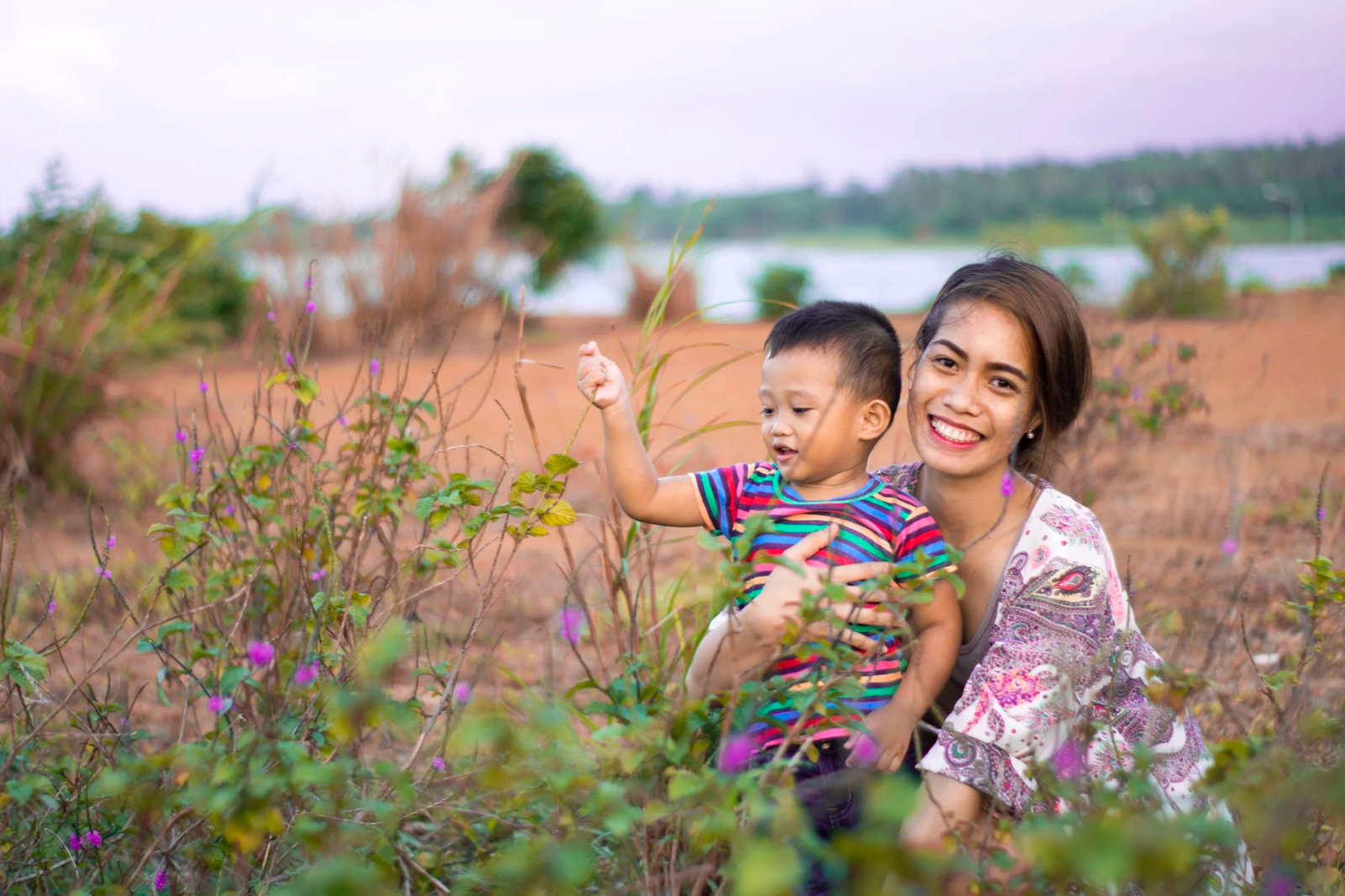 A young mother and her sun smiling in a field as the sun plays with the reeds