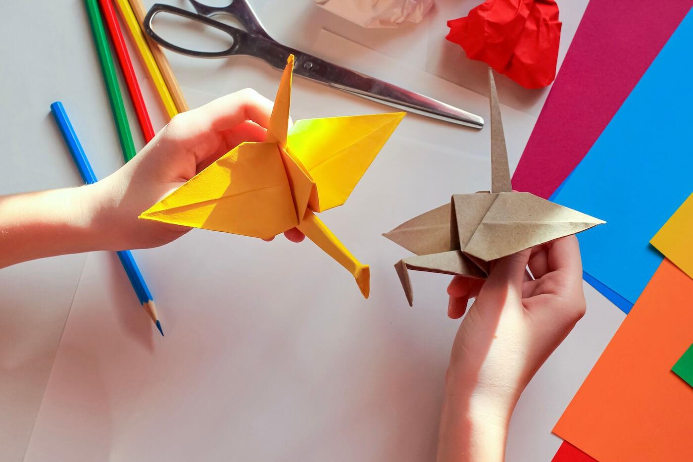 crianças segurando origamis coloridos