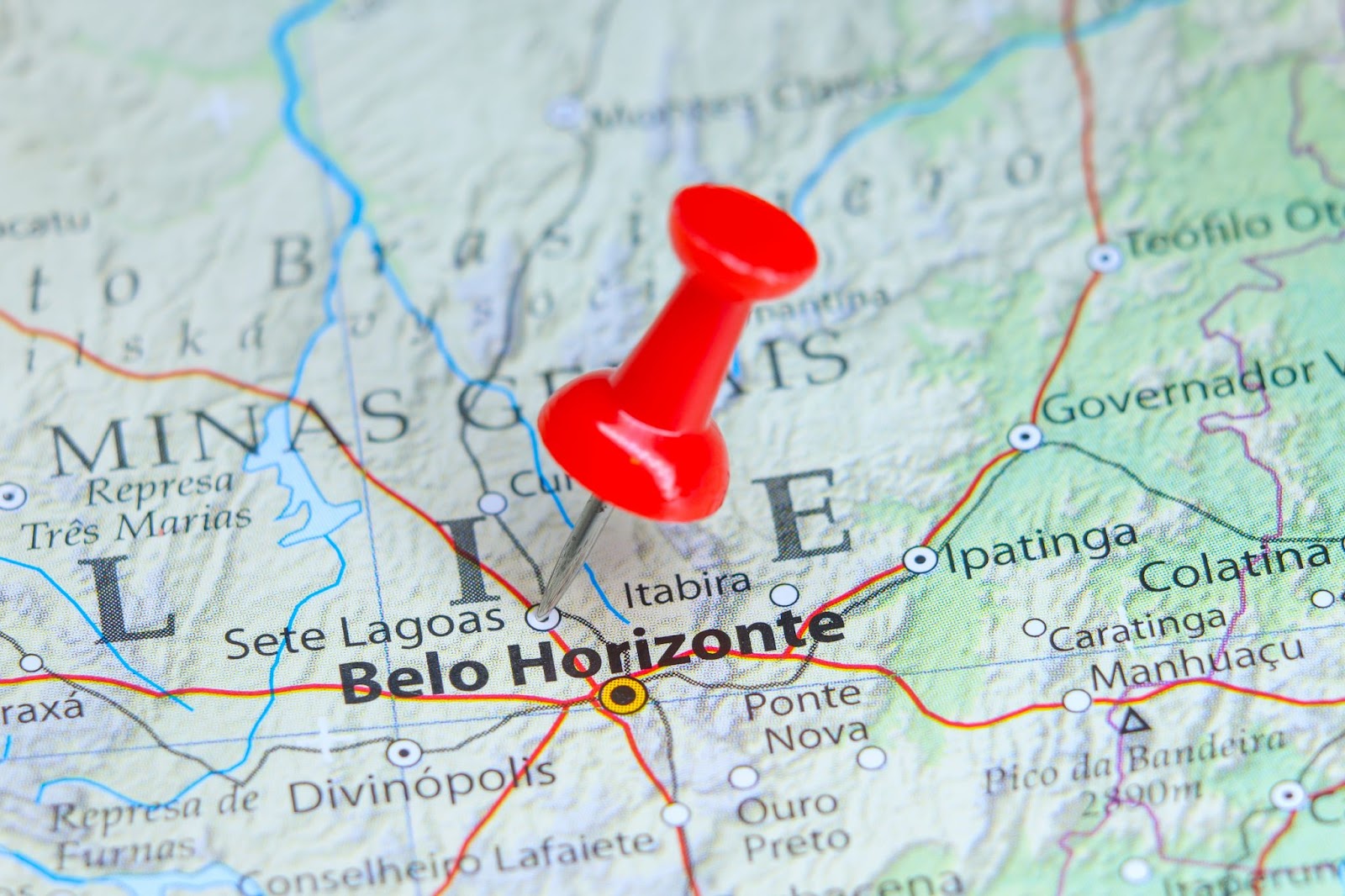 Mapa de Minas Gerais com pin vermelho na cidade de Sete Lagoas, logo acima da capital Belo Horizonte.