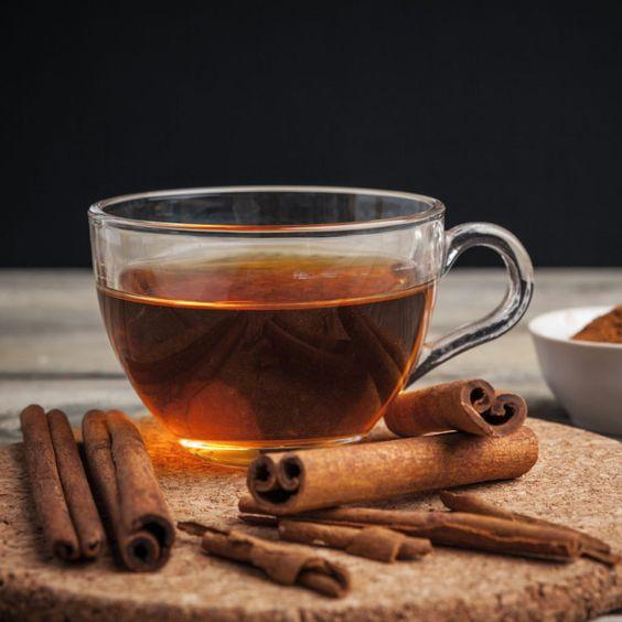 A glass cup of tea with cinnamon sticks and a bowl of powder

Description automatically generated