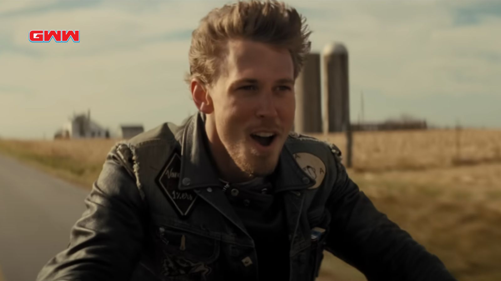 Benny riding a motorcycle, looking excited, farm buildings in background.