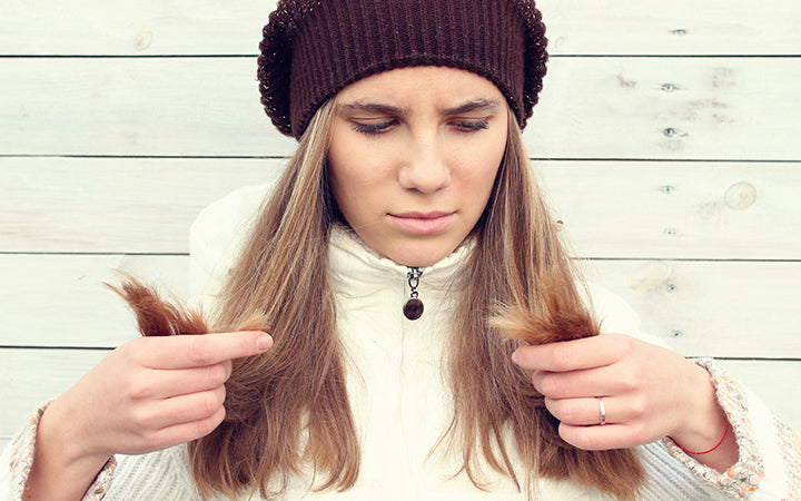 girl is looking at her hair in the process of  winter hair care