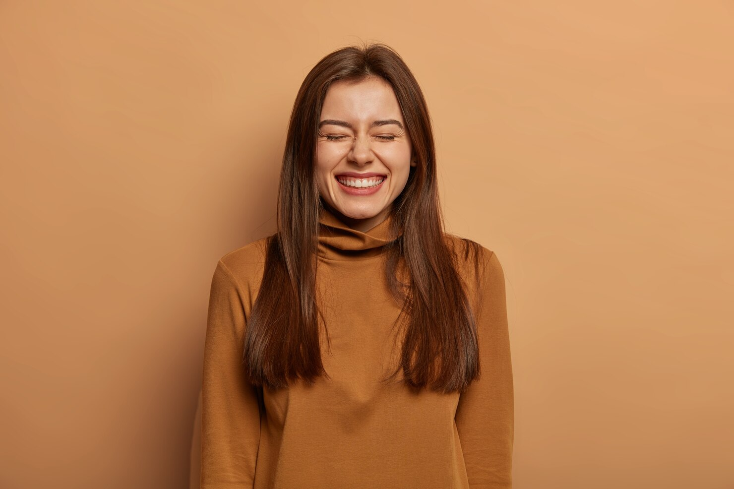 A woman laughing with her eyes closed thinking about funny meme captions.