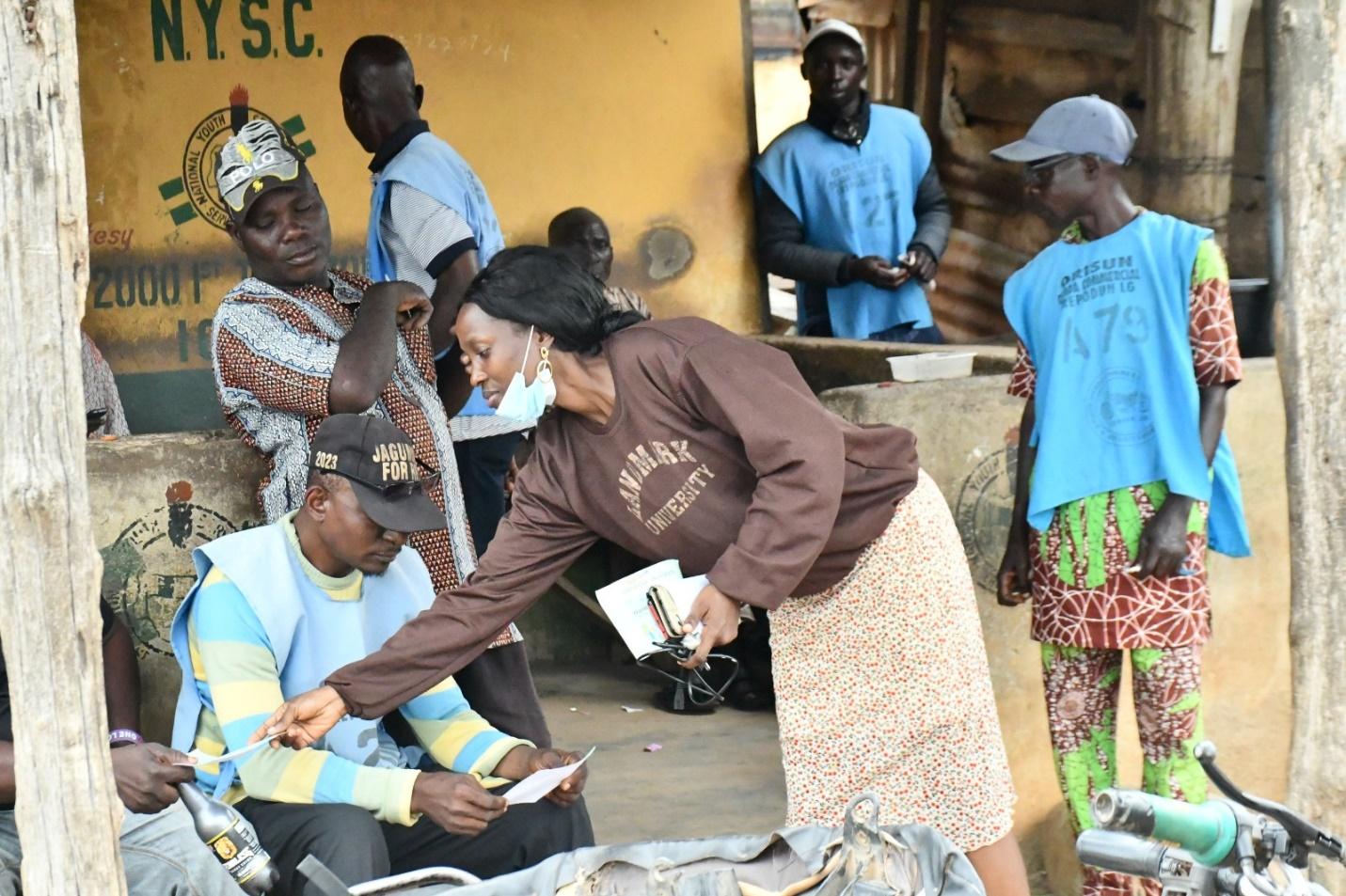 C:\Users\HP\Desktop\13 3 4\A member of the SDG 11 distributing flyers to some residents of Omuaran town as part of the sensitization exercise.jpeg