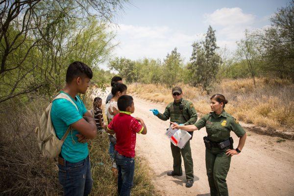 Nhân viên Tuần tra Biên giới nói chuyện với những trẻ vị thành niên không có người đi kèm vừa vượt qua biên giới Hoa Kỳ-Mexico, trước khi đưa họ lên xe tải để vận chuyển đến một cơ sở của Văn phòng Tị nạn và Tái định cư, ở Quận Hidalgo, Texas, vào ngày 26/05/2017. (Ảnh: Benjamin Chasteen/The Epoch Times)