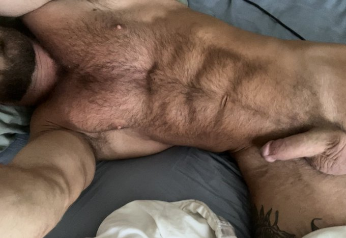 Bruce Jones taking a selfie lying down on the bed naked showing off his semi hard circumcised penis
