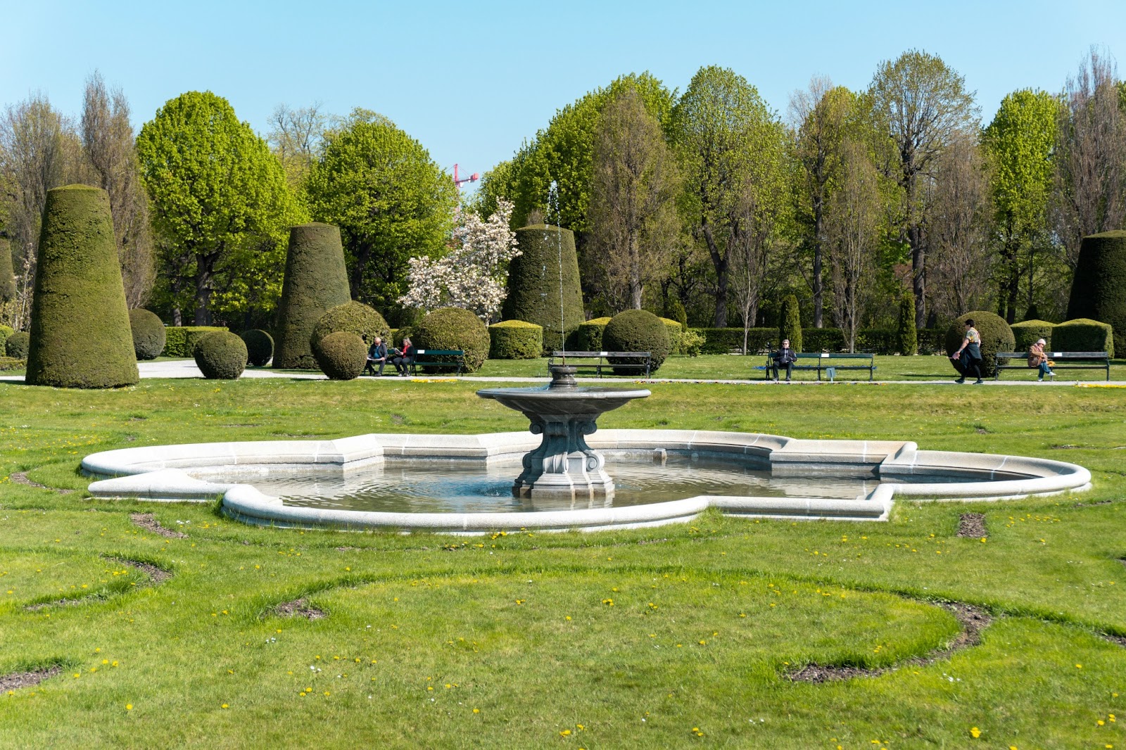 Tranquil scene in Schönbrunn Palace's Baroque gardens, with lush greenery and sculpted features.