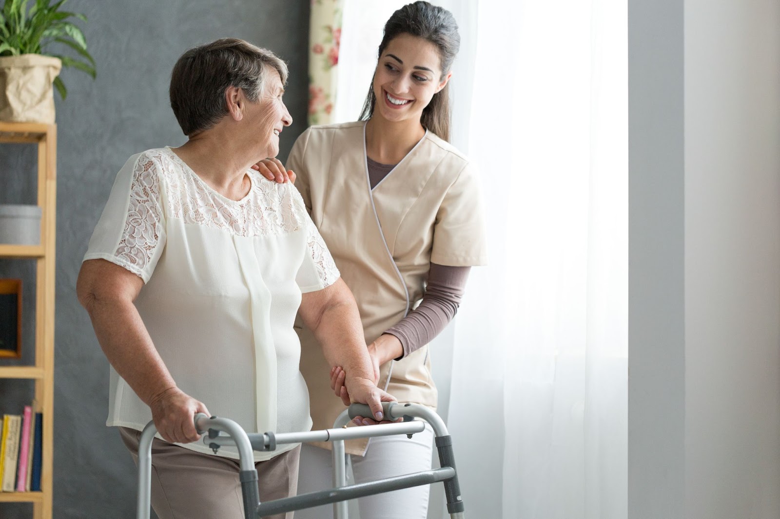 caregiver with senior lady using walker in living room