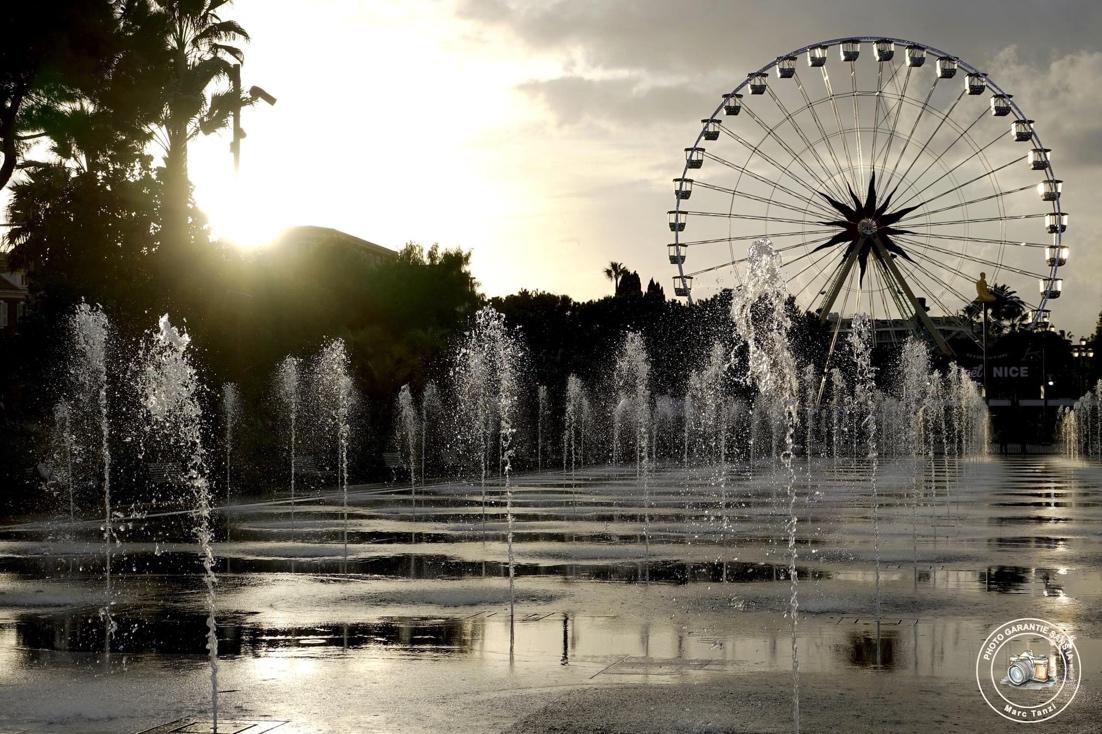 A water fountain with a ferris wheel in the background

Description automatically generated