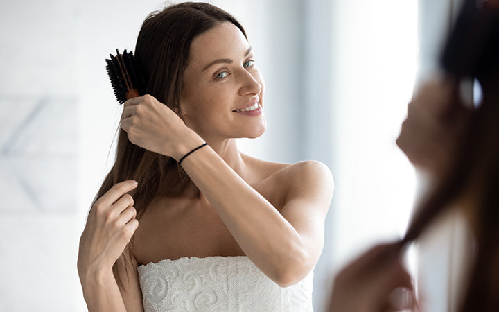 young lady model brushing long healthy hair look in mirror