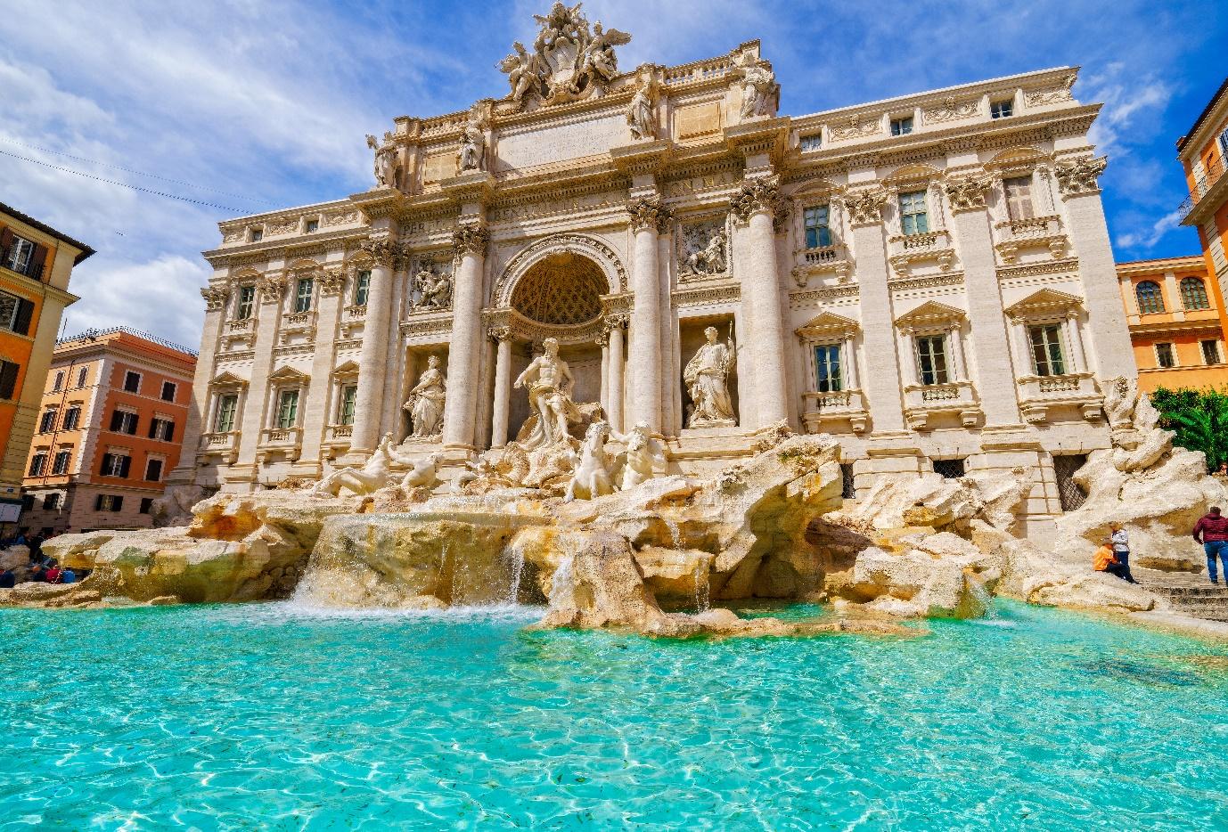 A large building with a fountain in front with Trevi Fountain in the backgroundDescription automatically generated