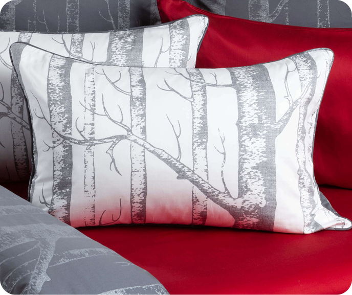 Our Birchgrove Pillow Sham shown on a bed with red sheets.