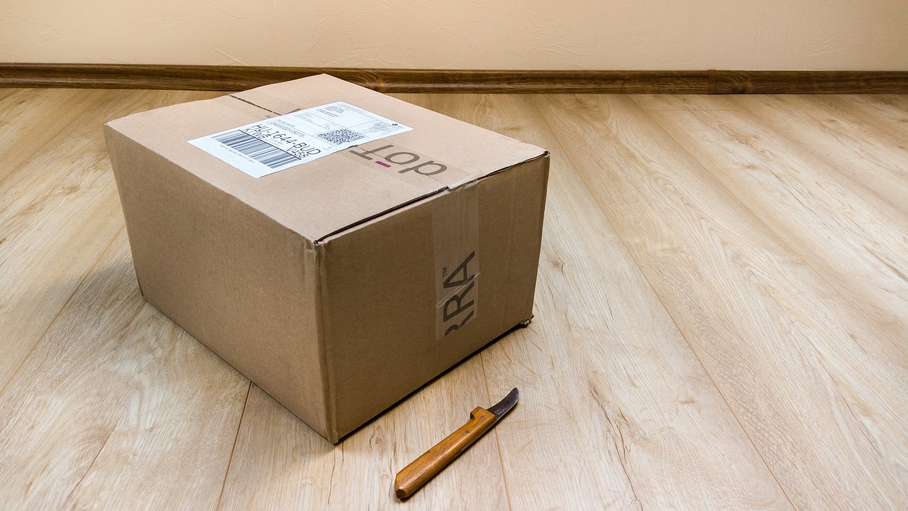 a cardboard box next to a box cutter on a wooden floor