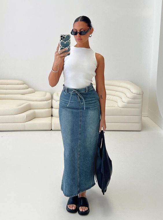 2024 fashion trends: Picture of a lady taking a selfie while rocking a white tee and the denim maxi skirt