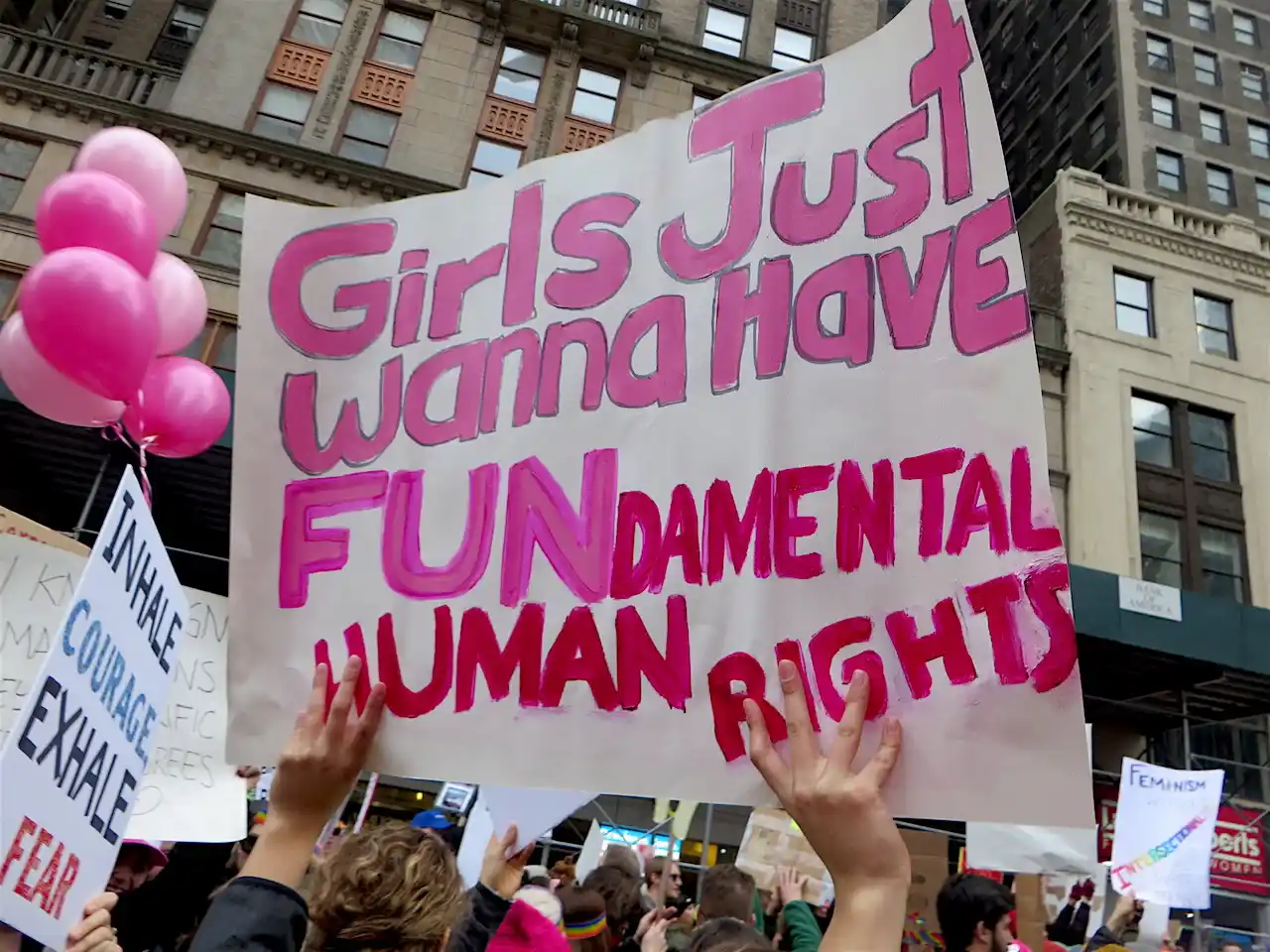 A group of people holding up a sign<br><br>Description automatically generated