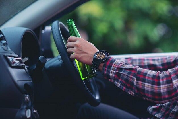 Free photo asian man holds a beer bottle while is driving a car