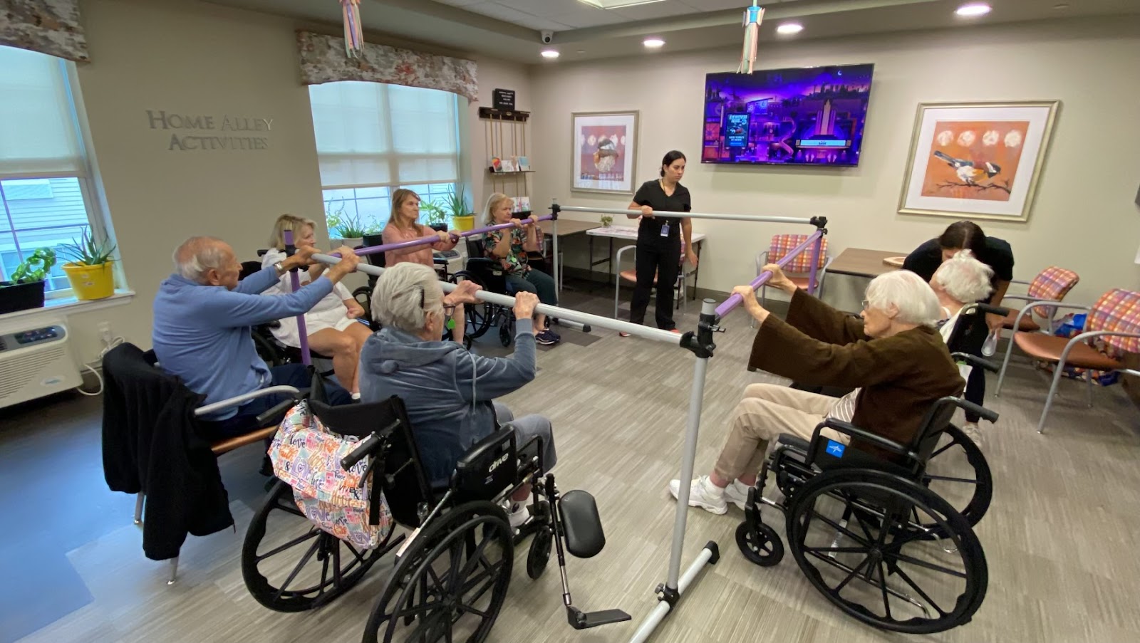 A group of seniors in wheelchairs receiving physical therapy help