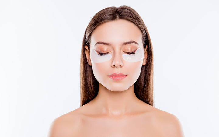 close up portrait of girl with shoulders using having applying patches under close eyes fight with dark circles