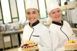 Students girls in pastry holding cakes