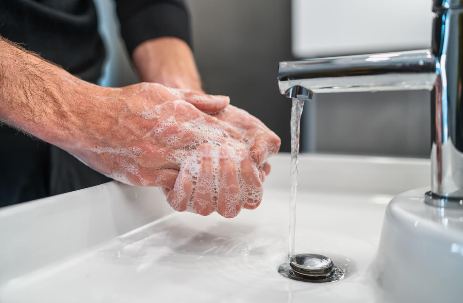 A man washing his hands using soap and water.