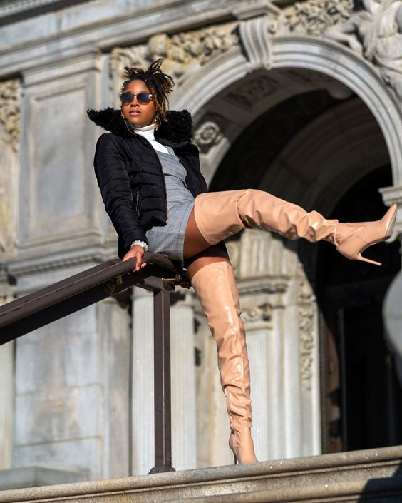 Picture of a lady dressing up her coat with thigh high boots and mini gown