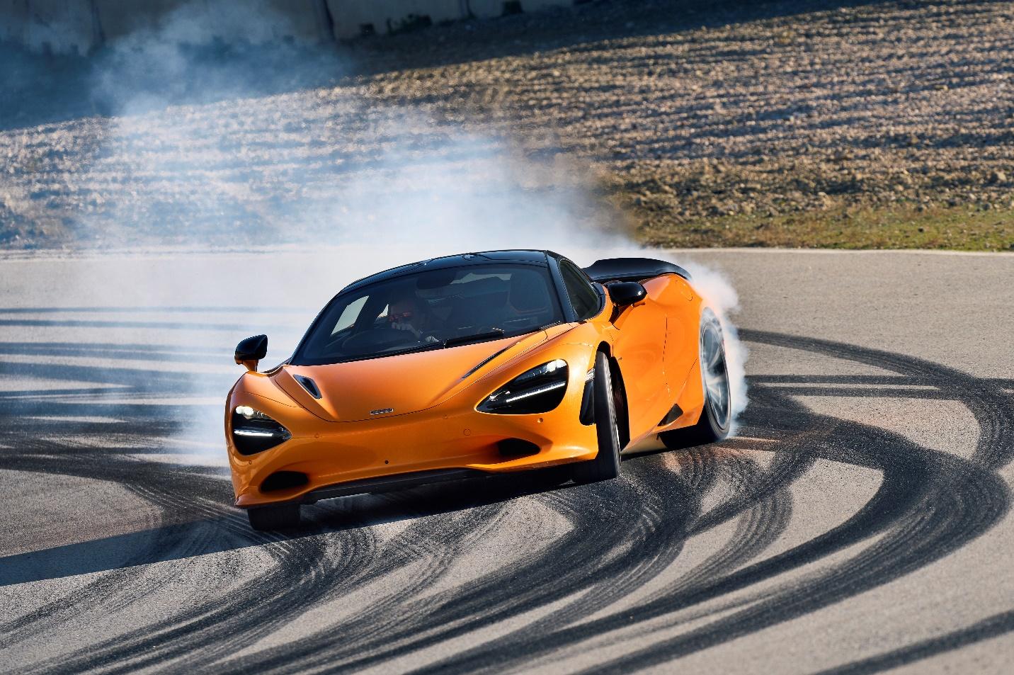 A orange sports car on a road with smoke coming out of it

Description automatically generated