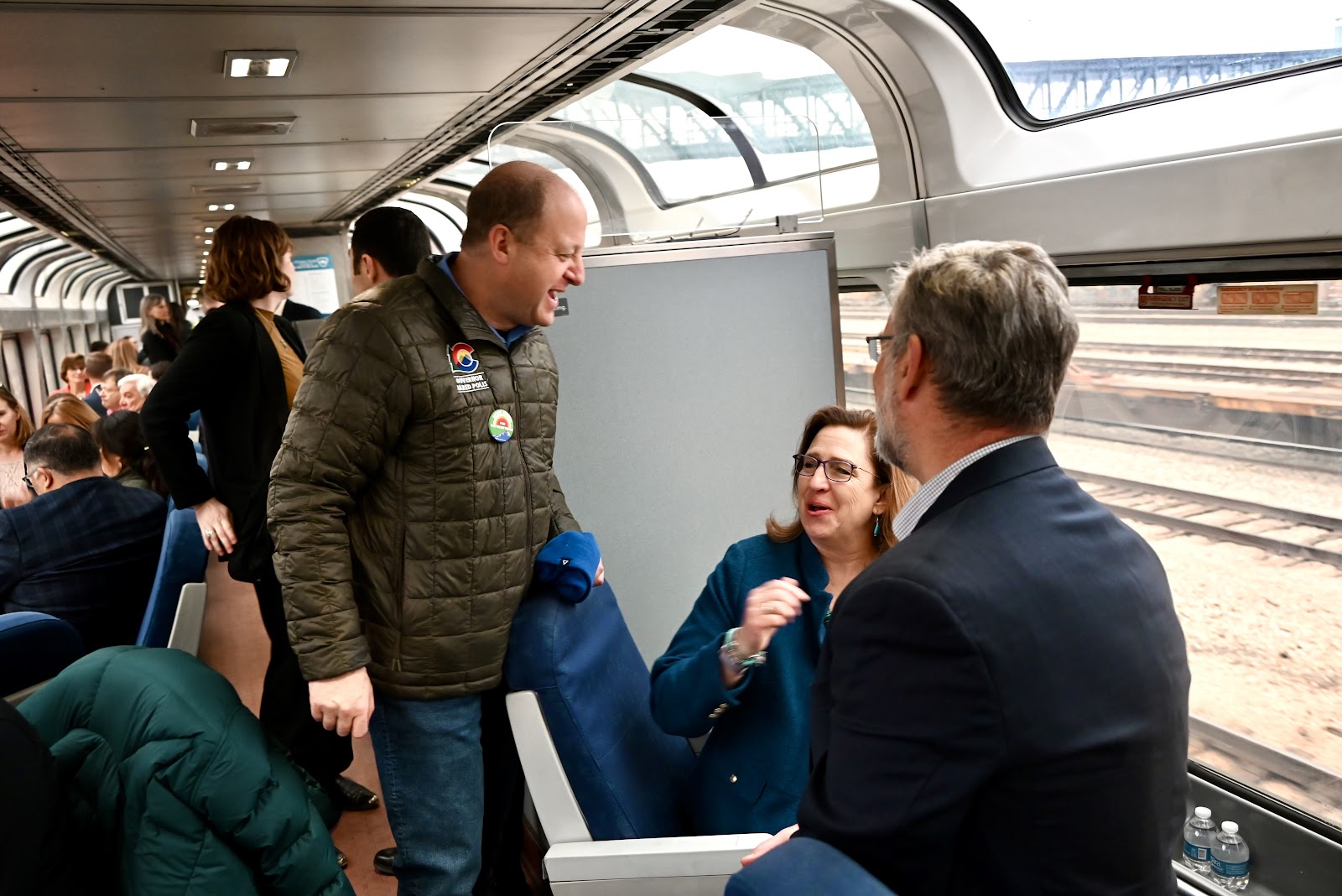 Governor Polis speaks with passengers on the train during the ride.
