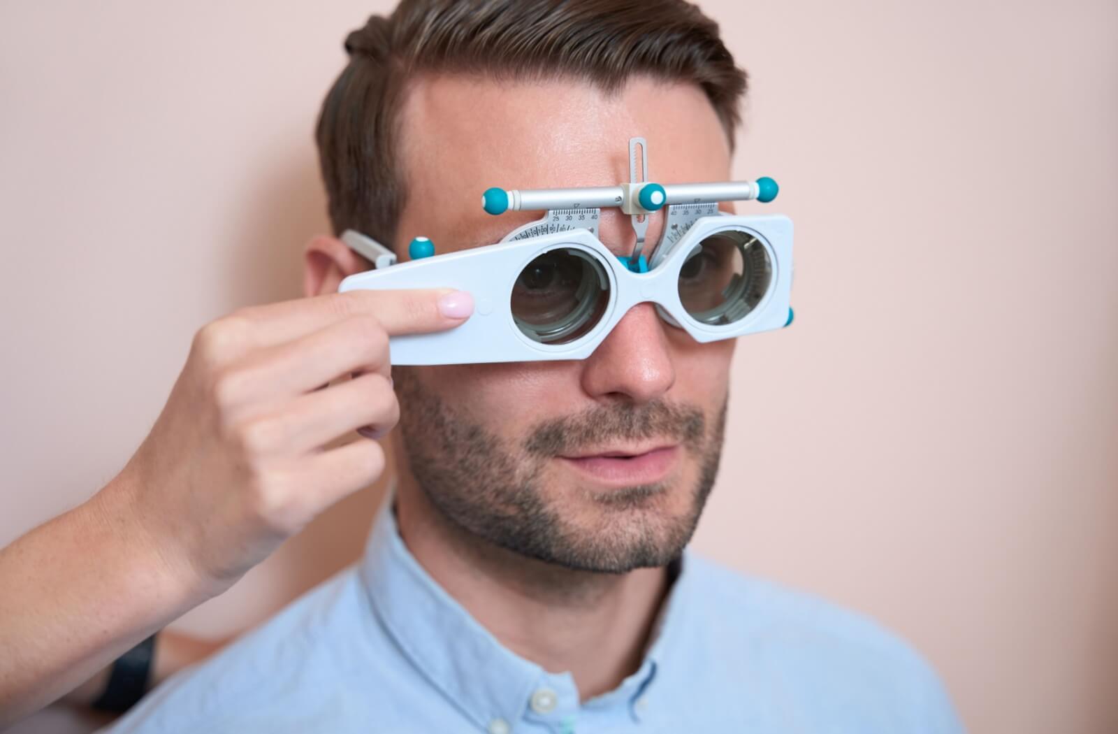 A man in a blue shirt undergoing visual acuity test as a part of his comprehensive eye exam.