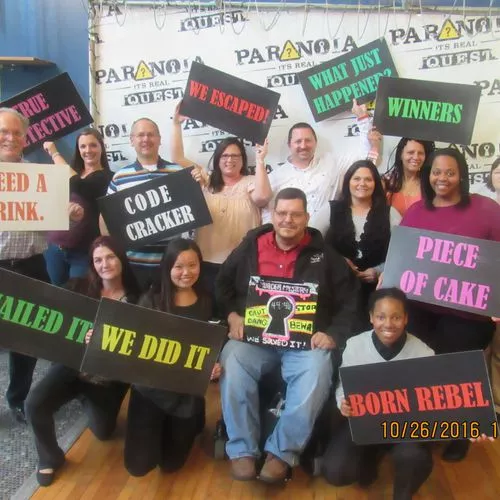 A team holding banners after a winning an escape game at Paranoia Quest, Atlanta.  