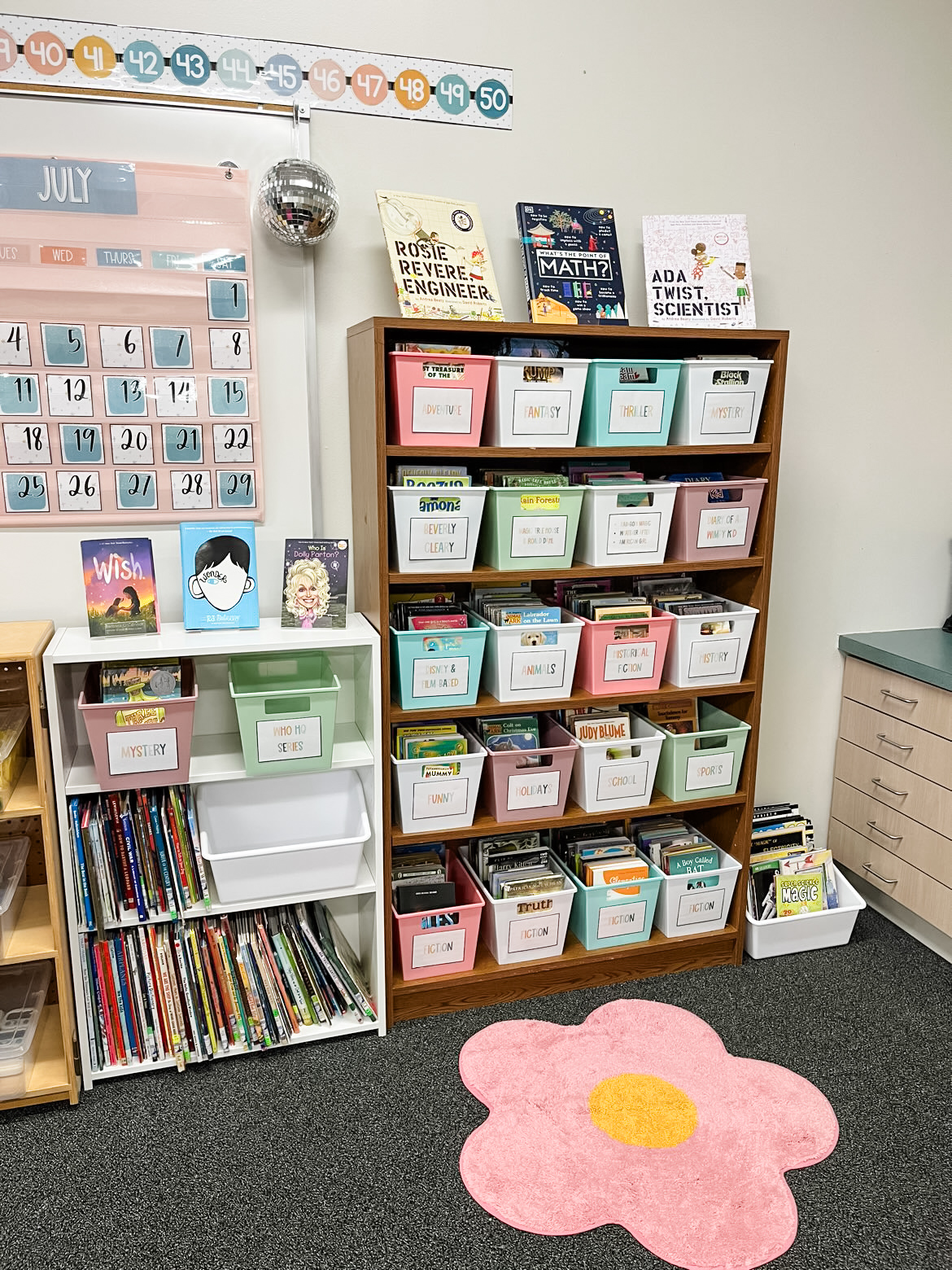This image shows classroom library ideas using two bookshelves. One bookshelf is lower and has picture books stored there. The other bookshelf is tall and has books organized in buckets by genres. 