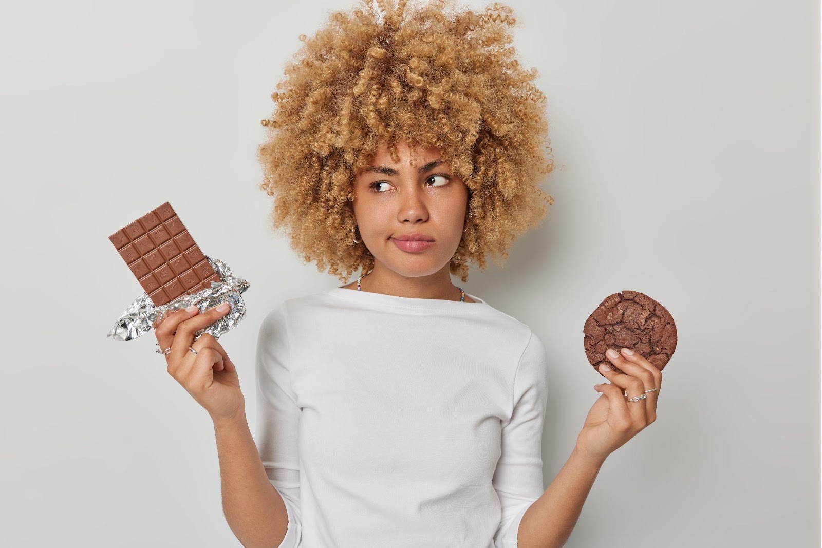 mulher com barra de chocolate e cookie em mãos