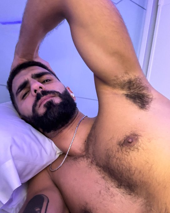 karim yoav lying naked in bed and holding his head