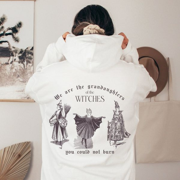 foto de una mujer con una sudadera con capucha blanca con un estampado de bruja en la espalda