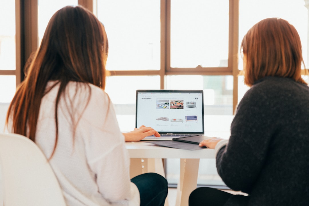 Two women, working together on a laptop.