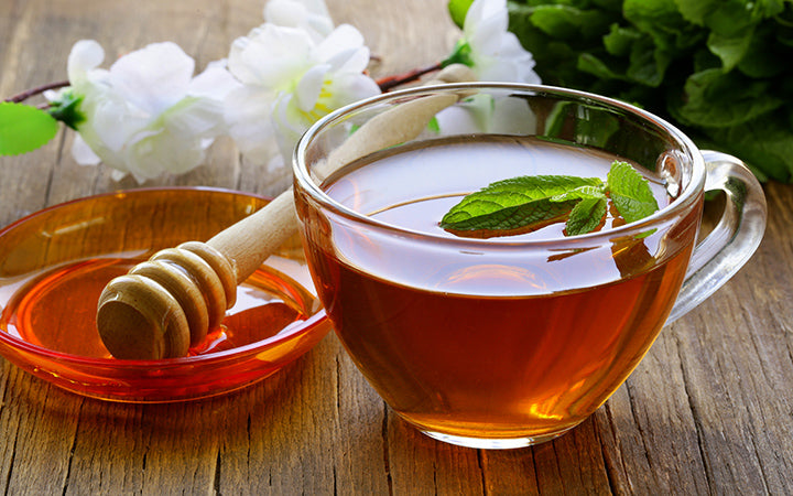 cup of tea with mint and honey on a wooden table