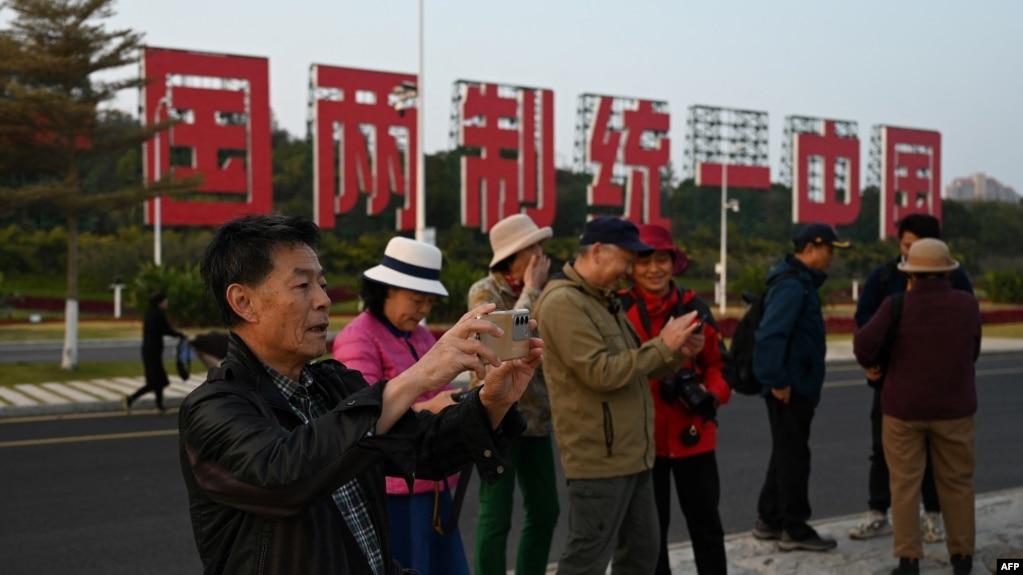 中国福建厦门竖立起一个台湾金门岛可以看到的“一国两制统一中国”的大型标语牌,旅游者在前拍照。(2024年1月12日)