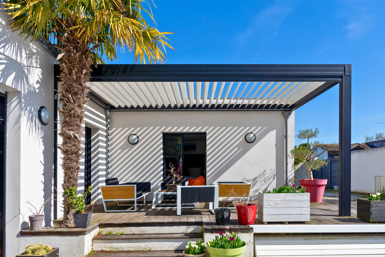 An open manual louvered pergola on an outdoor space with decking