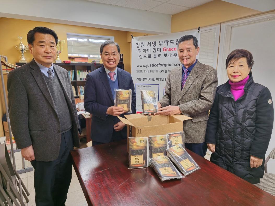 A group of people standing next to a box of books

Description automatically generated