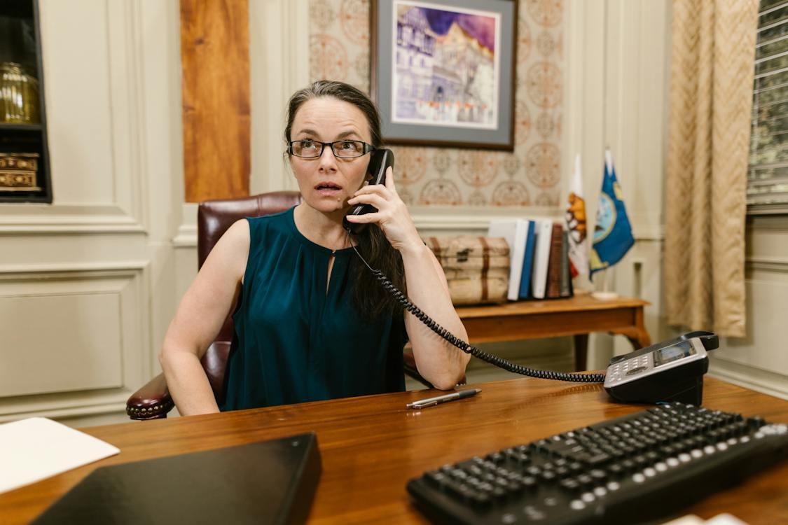 Free A Woman Talking on the Phone at her Work Desk Stock Photo