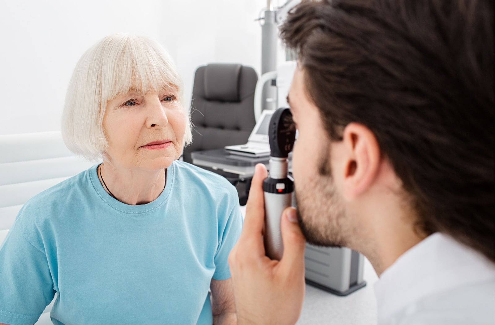 A male optometrist examines a female patient's eyes for cataracts