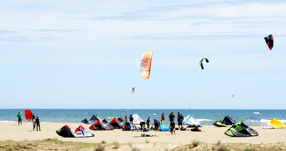 kiteboarders gather on the beach.
