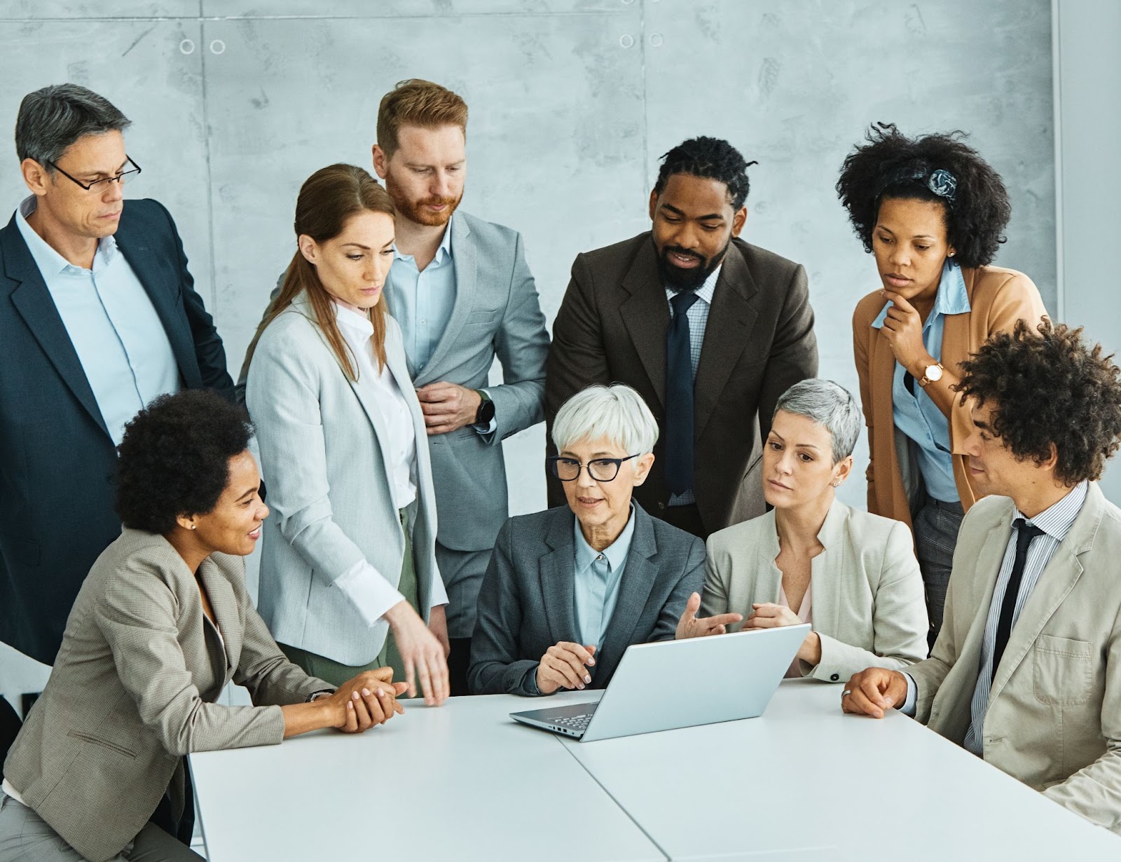 A group of business professionals looking at a laptop and discussing important strategies. 