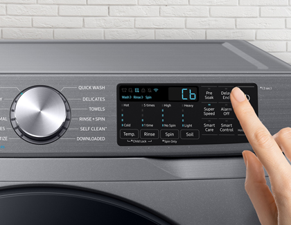 A finger adjusting the settings on the control panel of a Samsung washing machine.