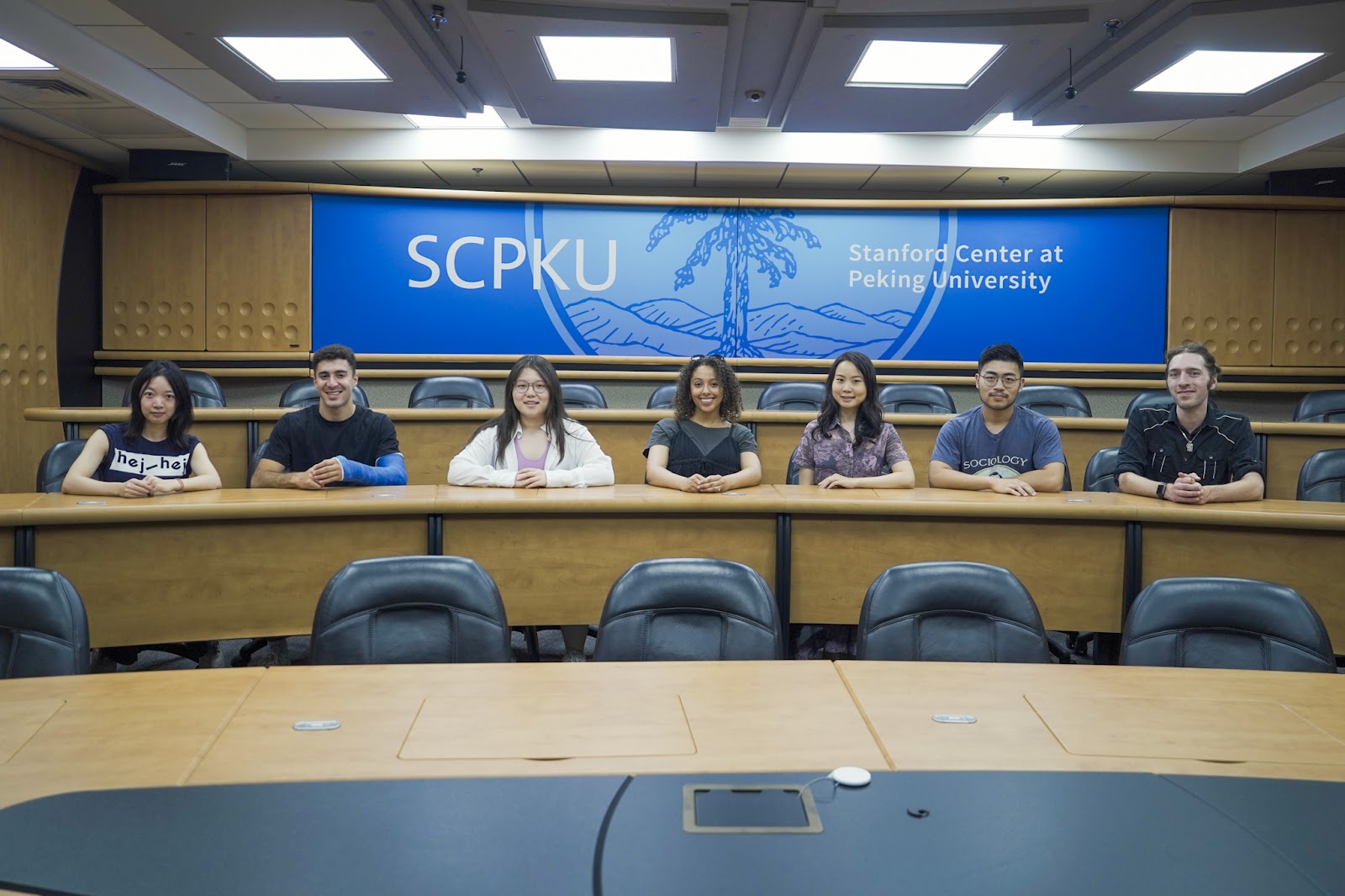 Photo of SCPKU students sitting at a table, with a program banner behind them