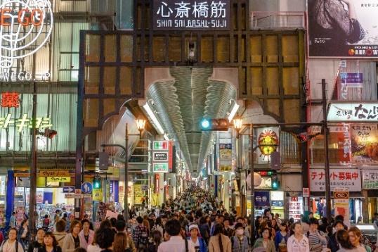 A group of people walking in a crowded street
Description automatically generated