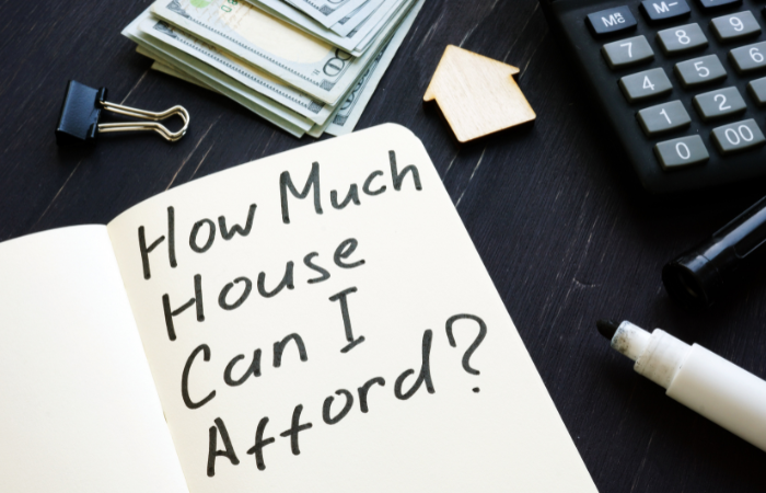 Notebook with "How Much House Can I Afford?" alongside money, keys, and a calculator, addressing real estate affordability.