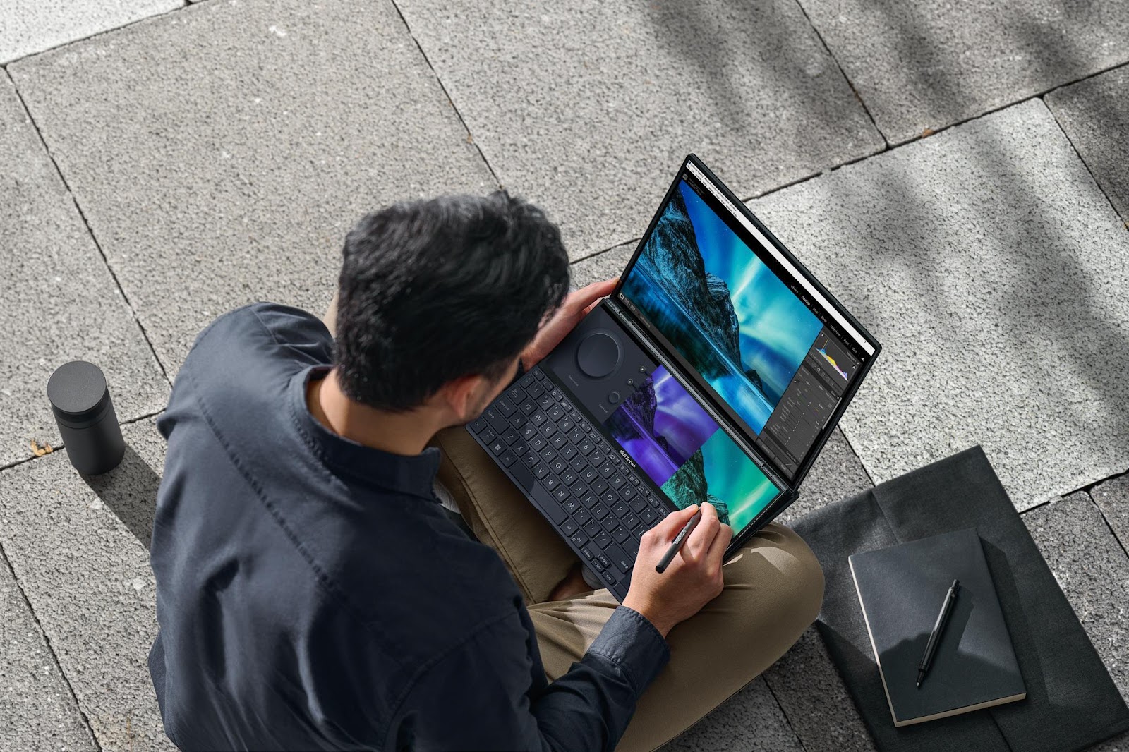 A person sitting on the ground looking at a computer screen Description automatically generated with low confidence